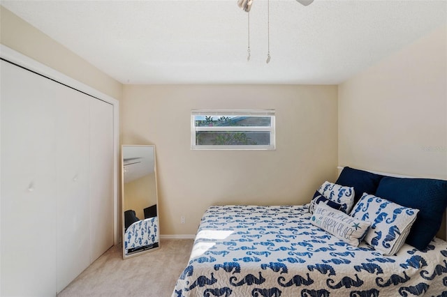 bedroom with ceiling fan, light colored carpet, a textured ceiling, and a closet