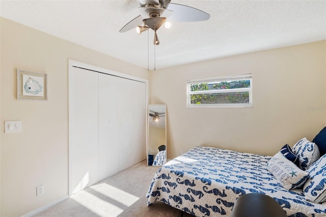 carpeted bedroom with a textured ceiling, ceiling fan, and a closet