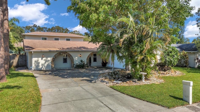 mediterranean / spanish-style home with fence, a front lawn, concrete driveway, and stucco siding