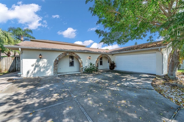 view of front of home featuring concrete driveway, fence, an attached garage, and stucco siding