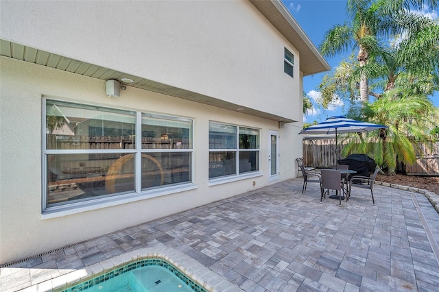 view of patio featuring fence, outdoor dining space, and a swimming pool