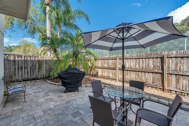 view of patio with area for grilling, a fenced backyard, and outdoor dining space