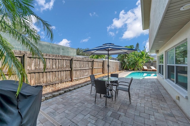 view of patio / terrace with a fenced in pool, a fenced backyard, outdoor dining space, and area for grilling
