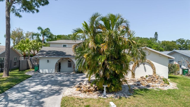 view of front of house with fence, a front lawn, stucco siding, and concrete driveway