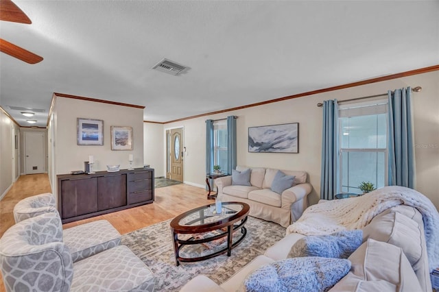 living area with a ceiling fan, baseboards, crown molding, and visible vents