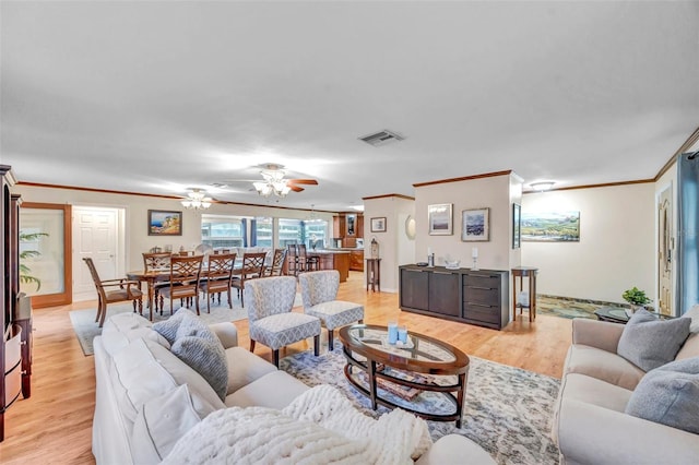 living area featuring light wood-style flooring, visible vents, ornamental molding, and a ceiling fan