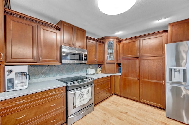 kitchen featuring light wood-style flooring, light countertops, brown cabinets, and appliances with stainless steel finishes