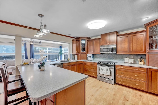 kitchen with brown cabinets, stainless steel appliances, glass insert cabinets, a peninsula, and tasteful backsplash