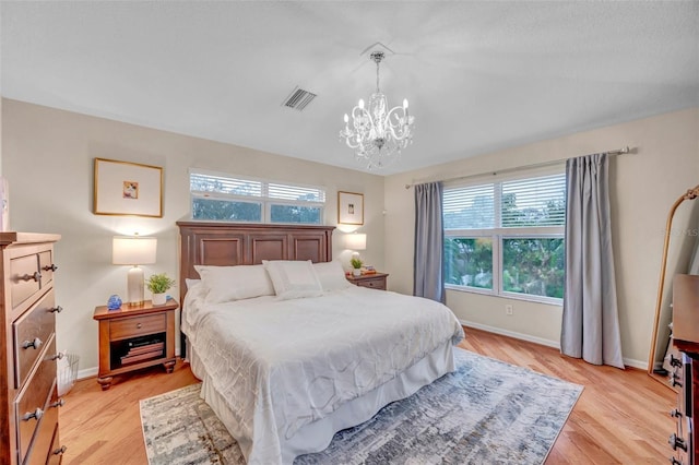bedroom featuring baseboards, light wood finished floors, a chandelier, and visible vents