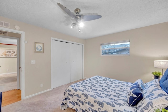 bedroom with a textured ceiling, visible vents, carpet, and a closet