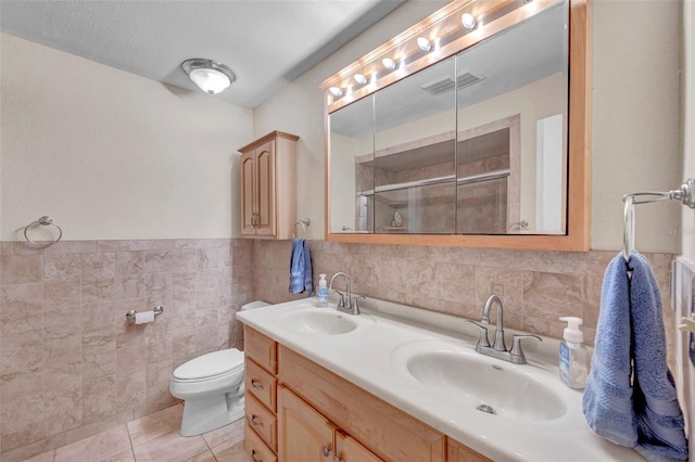 full bathroom with tile walls, tile patterned floors, an enclosed shower, and a sink