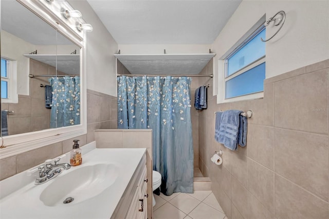 bathroom featuring toilet, tile walls, tiled shower, tile patterned flooring, and vanity