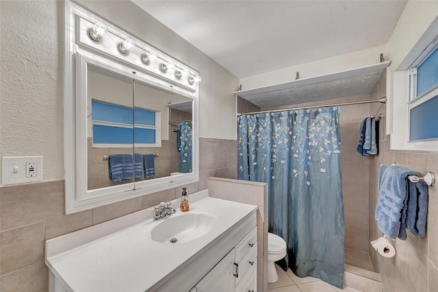 bathroom with tile walls, vanity, toilet, and tiled shower