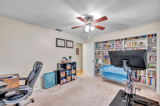 home office featuring carpet, visible vents, and a ceiling fan