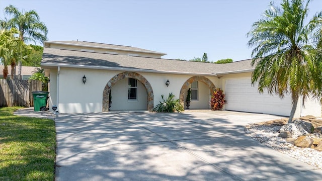 view of front of home featuring concrete driveway, fence, a garage, a shingled roof, and stucco siding