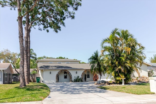 view of front of property featuring stucco siding, a front yard, concrete driveway, and fence