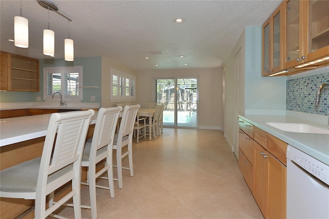 kitchen with decorative backsplash, dishwasher, sink, and hanging light fixtures