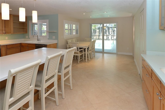 kitchen featuring a wealth of natural light, sink, hanging light fixtures, and a textured ceiling