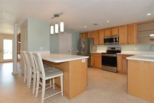 kitchen featuring a kitchen breakfast bar, stainless steel appliances, sink, decorative light fixtures, and a textured ceiling