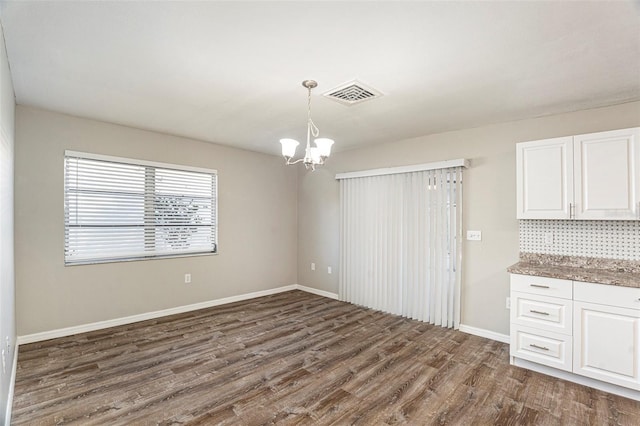 unfurnished dining area featuring dark hardwood / wood-style flooring and a notable chandelier