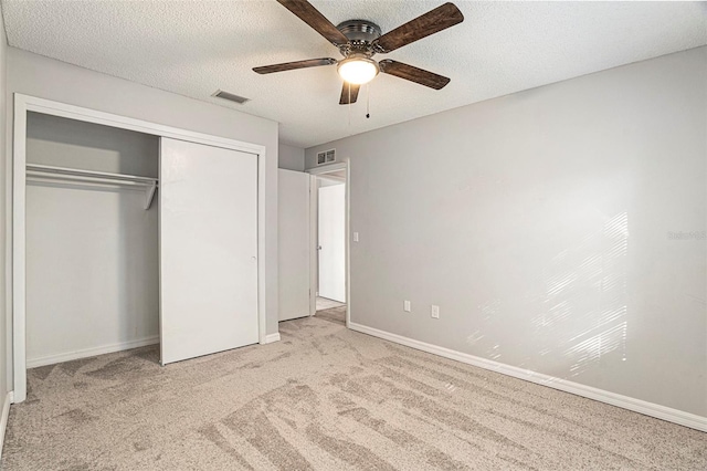 unfurnished bedroom featuring a textured ceiling, light carpet, ceiling fan, and a closet