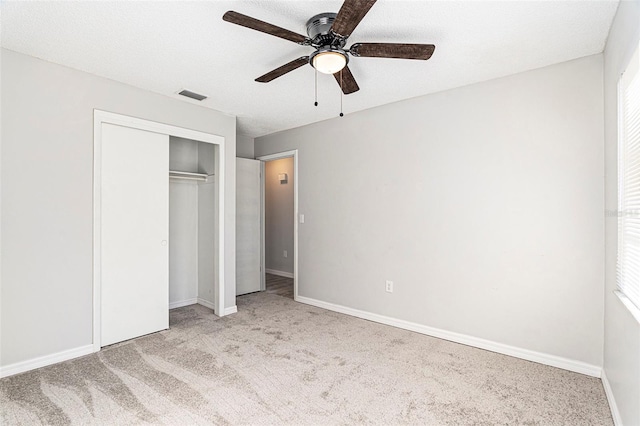 unfurnished bedroom with ceiling fan, a textured ceiling, a closet, and light colored carpet