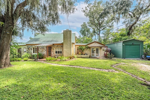 back of property with a garage, covered porch, an outdoor structure, and a yard