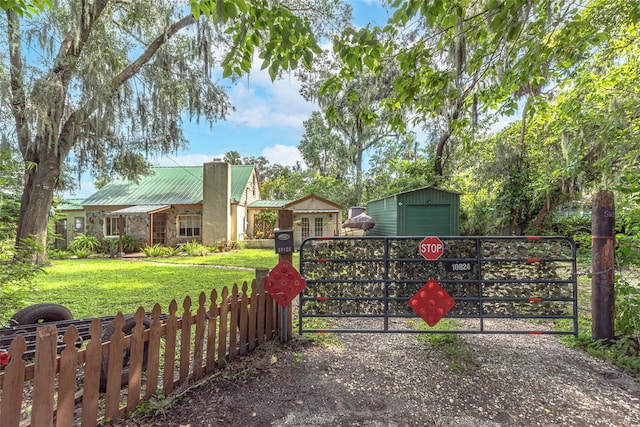 view of gate with a lawn and an outbuilding