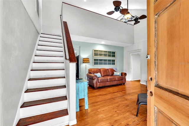 entryway featuring wood-type flooring, a towering ceiling, and ceiling fan