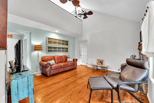 living room with a stone fireplace, hardwood / wood-style floors, and high vaulted ceiling