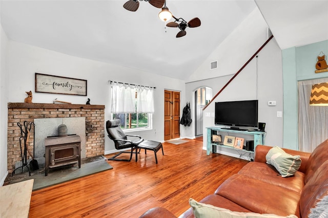 living room featuring ceiling fan, hardwood / wood-style flooring, a wood stove, and high vaulted ceiling