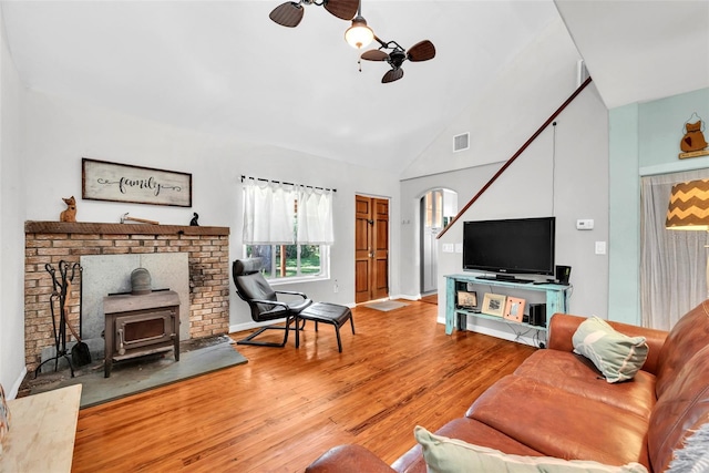 living room with high vaulted ceiling, a wood stove, ceiling fan, and hardwood / wood-style floors