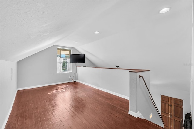 bonus room featuring a textured ceiling, dark hardwood / wood-style floors, and vaulted ceiling