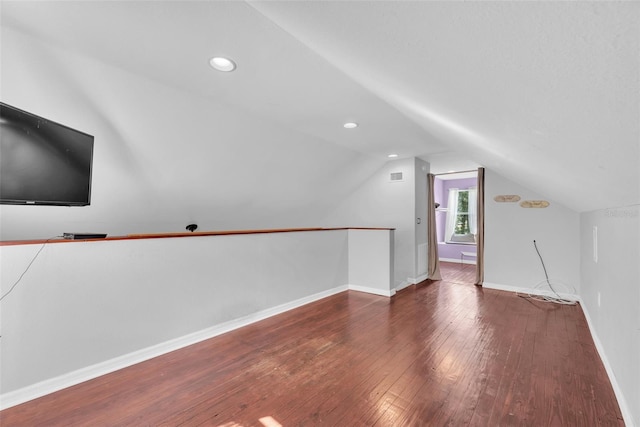 additional living space with vaulted ceiling and dark wood-type flooring