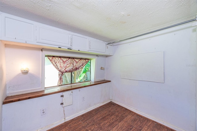 unfurnished room featuring a textured ceiling and dark hardwood / wood-style floors