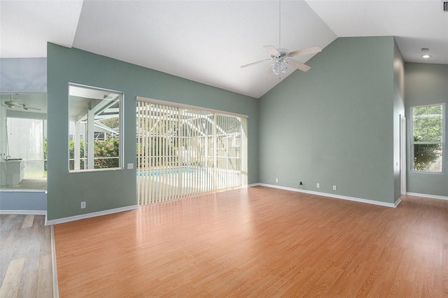 unfurnished living room featuring ceiling fan, light hardwood / wood-style flooring, high vaulted ceiling, and a wealth of natural light