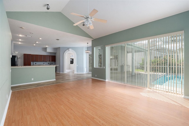 unfurnished living room with light hardwood / wood-style floors, high vaulted ceiling, and ceiling fan