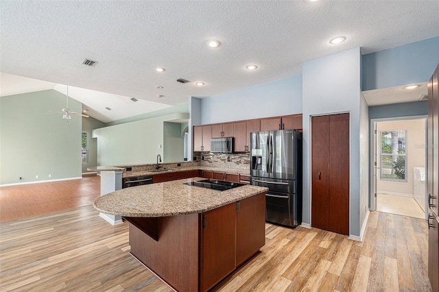 kitchen featuring stainless steel appliances, light hardwood / wood-style floors, a kitchen island, and a textured ceiling