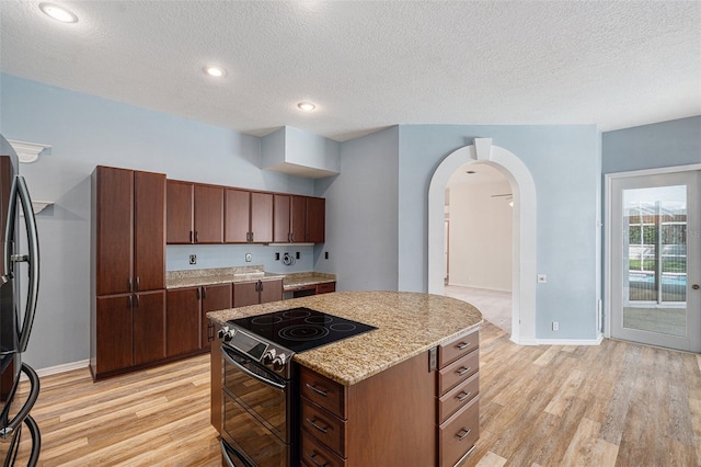 kitchen featuring black / electric stove, a textured ceiling, light wood-type flooring, and a center island