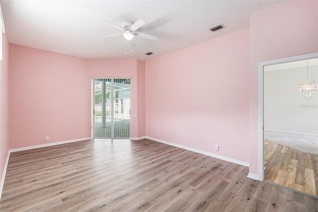 unfurnished room with ceiling fan with notable chandelier, a textured ceiling, and light hardwood / wood-style flooring