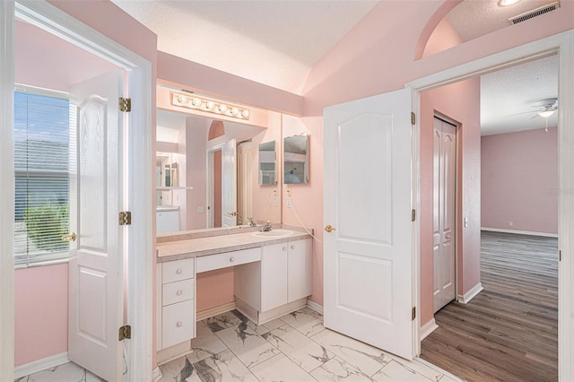 bathroom featuring ceiling fan, vanity, lofted ceiling, and plenty of natural light