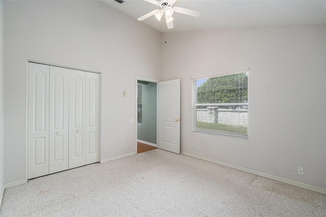 unfurnished bedroom with ceiling fan, a closet, light carpet, and high vaulted ceiling