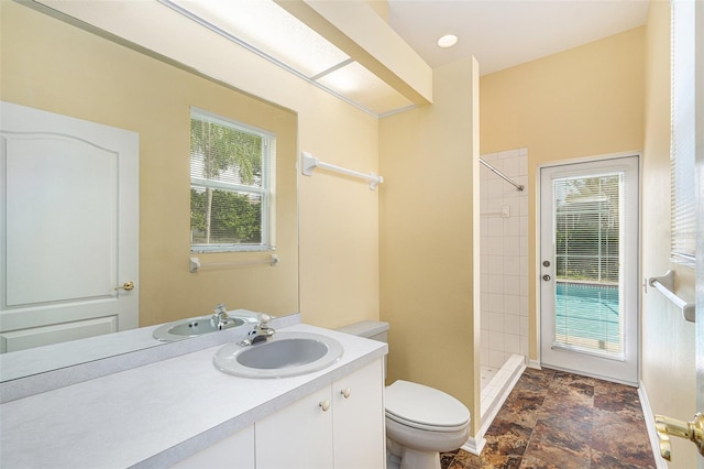 bathroom with a tile shower, vanity, and toilet