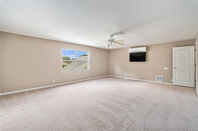 empty room featuring light carpet, an AC wall unit, a textured ceiling, and ceiling fan