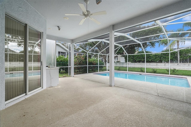 view of pool featuring glass enclosure, ceiling fan, and a patio