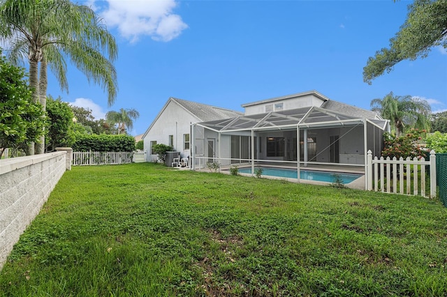 back of property with a fenced in pool, a lawn, and a lanai