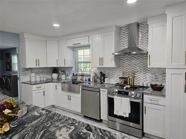 4810 N Galloway Rd, Lakeland, FL 33810 - kitchen with wall chimney exhaust hood, stainless steel appliances, washing machine and dryer, a sink, and white cabinetry