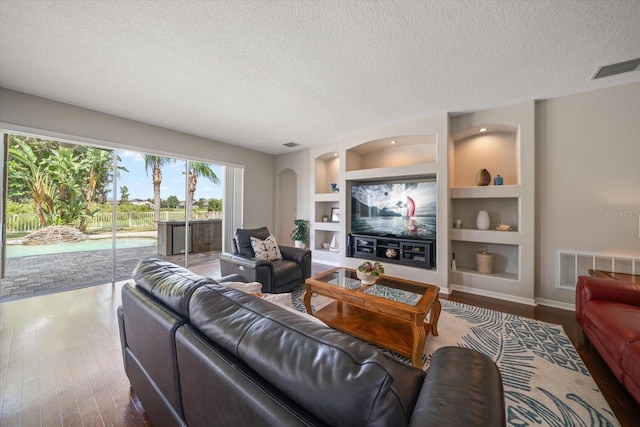 living room featuring wood-type flooring, a textured ceiling, and built in features