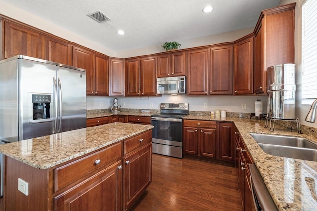 kitchen with light stone counters, stainless steel appliances, a textured ceiling, dark hardwood / wood-style floors, and sink