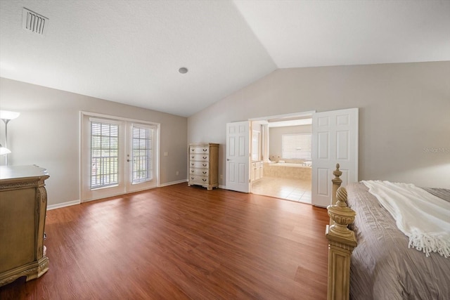 bedroom with hardwood / wood-style flooring, lofted ceiling, ensuite bath, and access to exterior